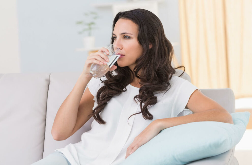 Woman sitting on couch drinking water.