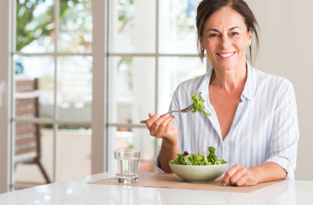 Smiling woman eating salad.