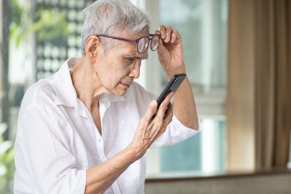 A senior woman struggling to read her phone due to macular degeneration.